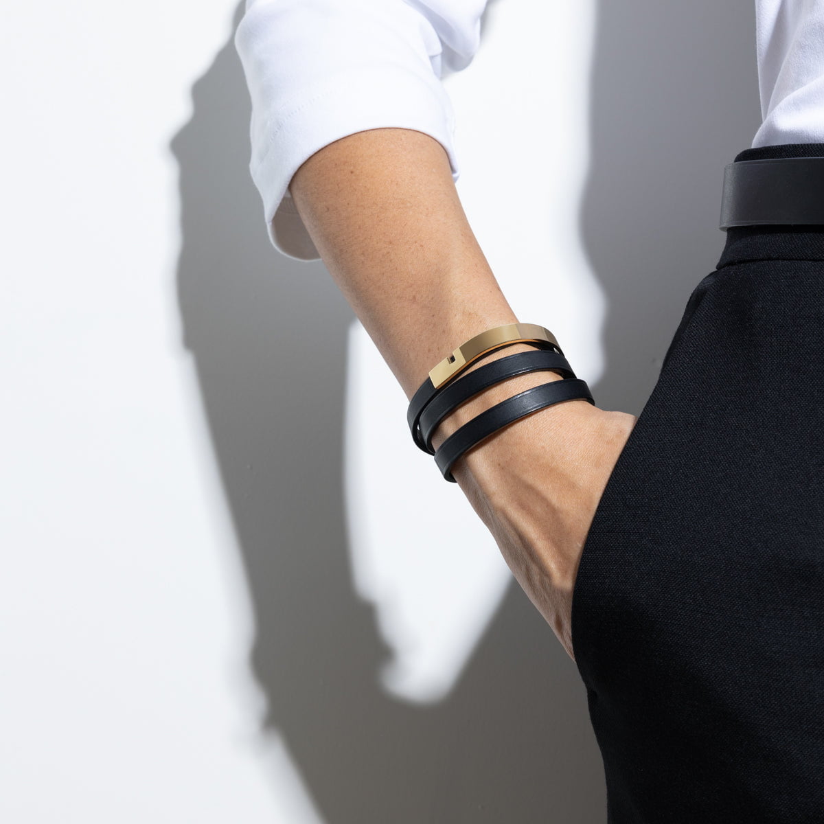 photo d'un bracelet cuir noir et or porté par une femme au stye minimaliste