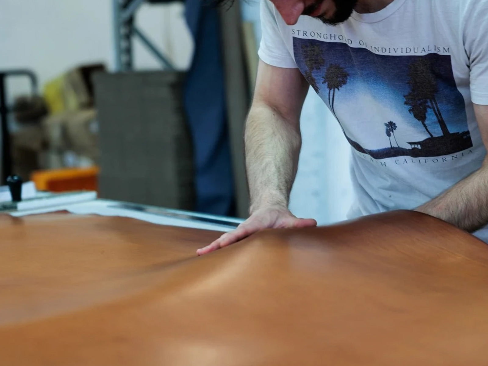 Sélection des peaux pleine fleur, main inspectant le grain du cuir dans l’atelier