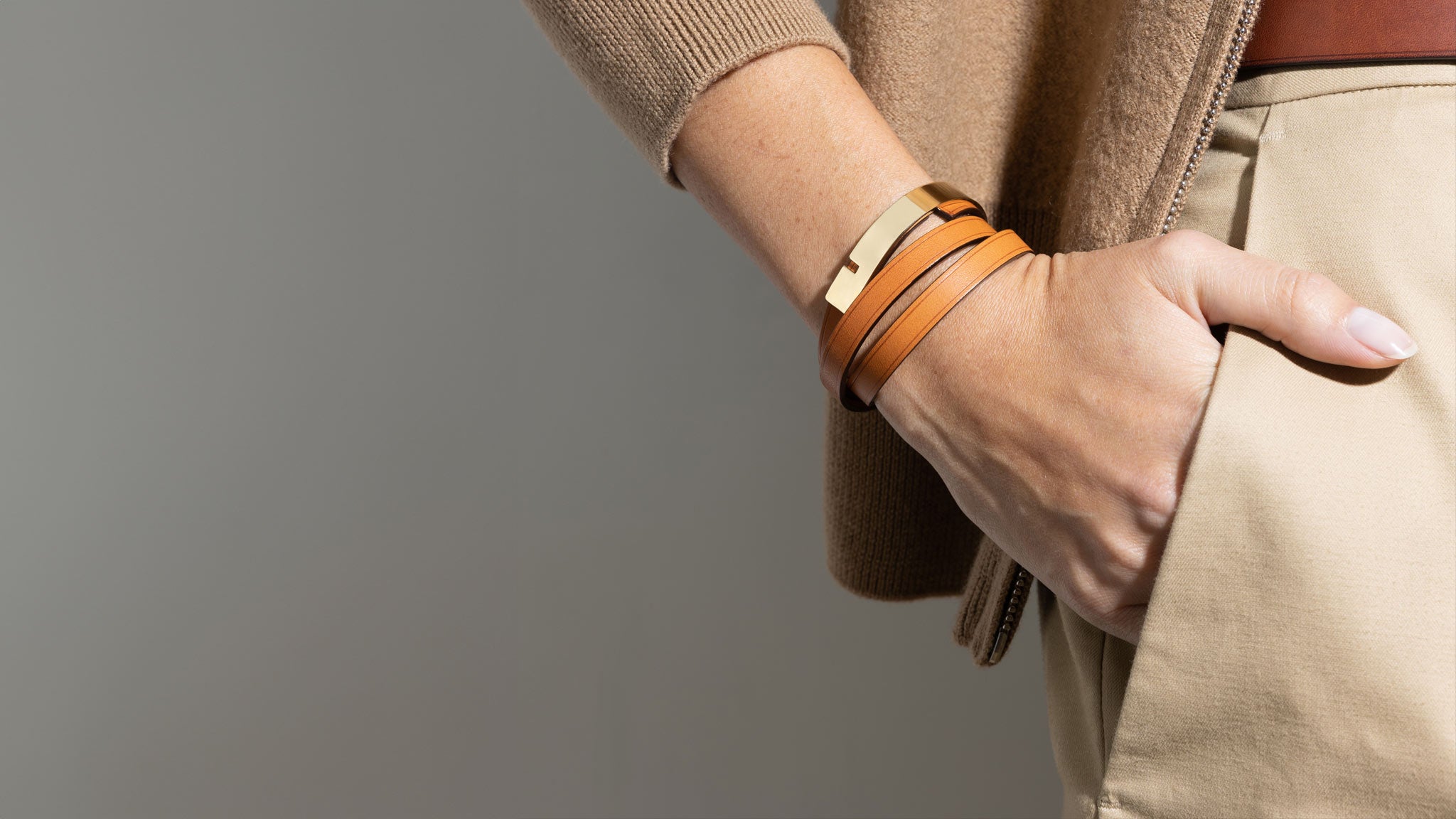 Bracelet cuir camel U-TURN TRIPLE porté au poignet, fermoir or, geste main dans la poche — Ursul Paris